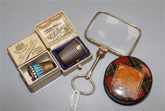 A gold plated magnifying glass, a silver gilt and enamel thimble, another thimble and a tartanware stamp box